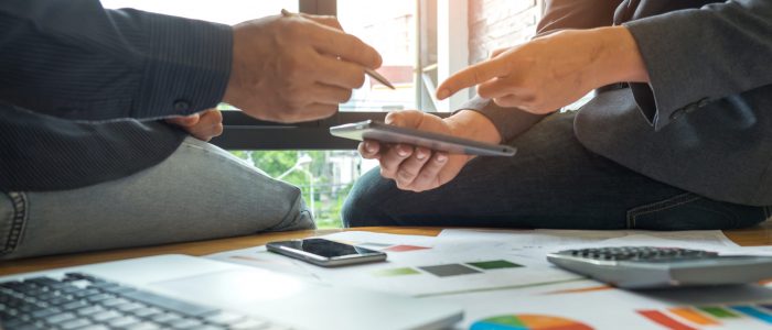 Business concepts,Two men are consulting a business with tablet Business concepts,Two men are consulting a business,Two men pointing at a tablet, laptop , graphs , calculator and smart phone on the desk.