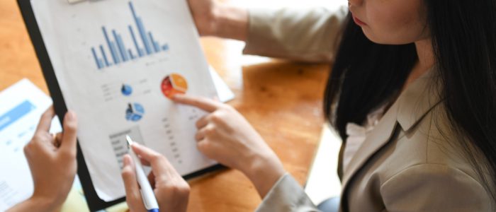 Female office worker holding graphs data sheet. They point to graphs for data analysis.